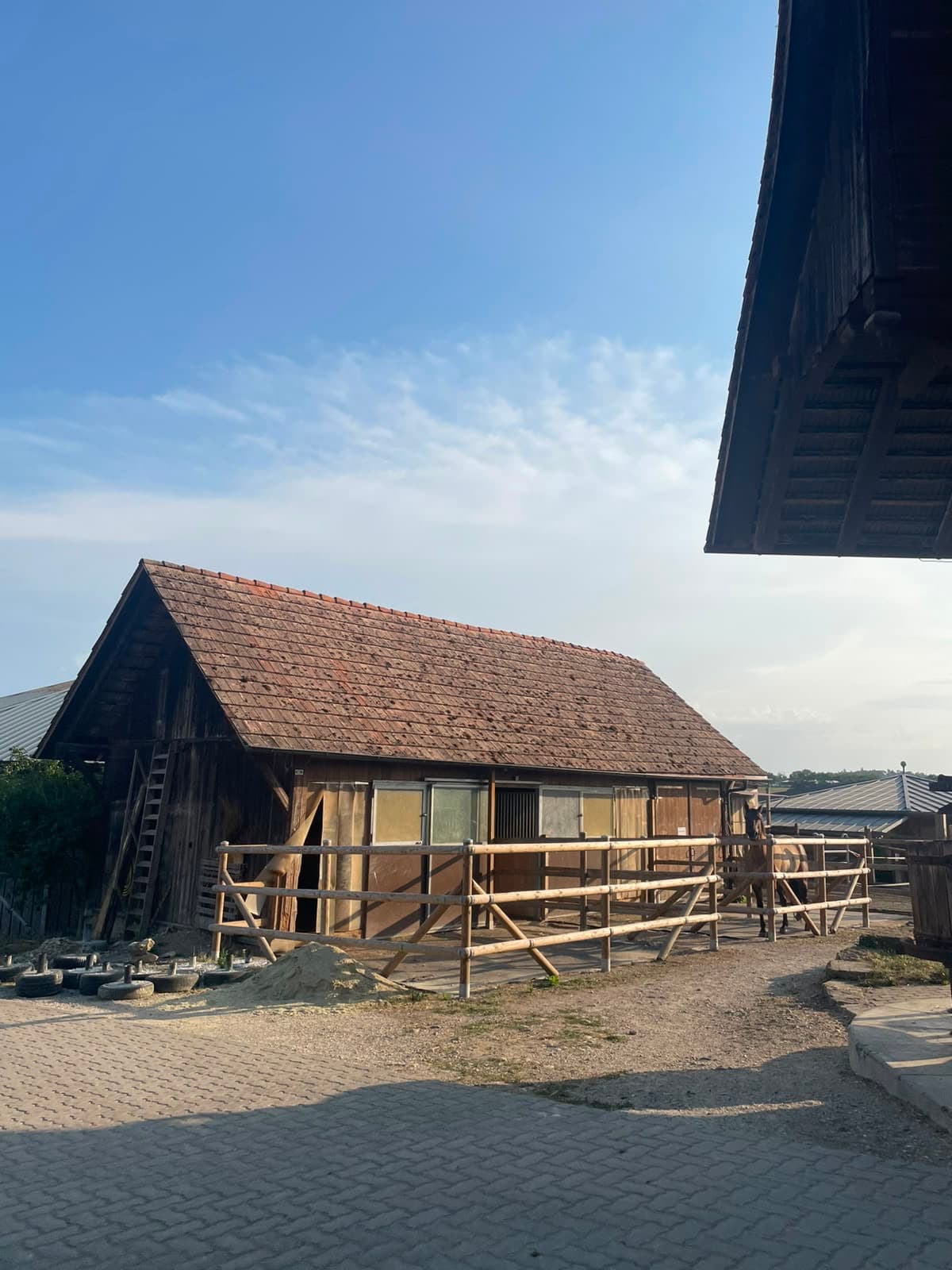 Stallgebäude mit Innenboxen und angrenzendem Auslauf mit Holzumzäunung